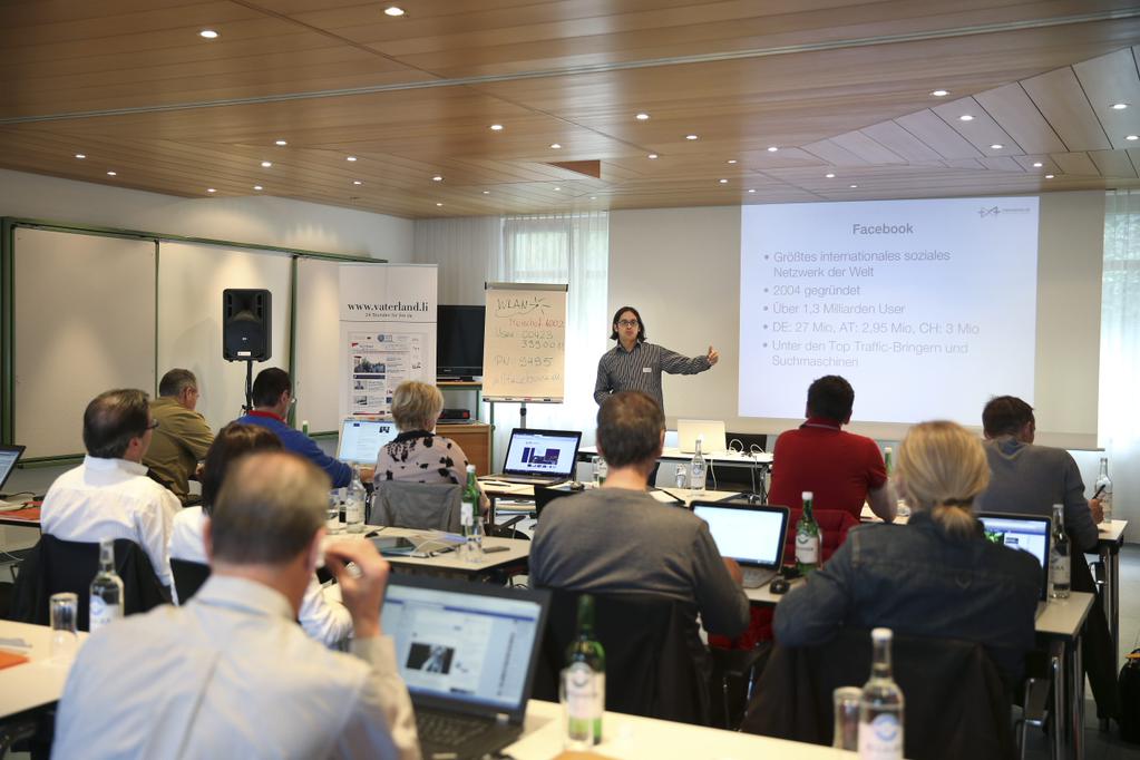Social-Media-Workshop in einem Seminarraum: Referent vor einer Gruppe von Teilnehmenden mit Laptops und Präsentation